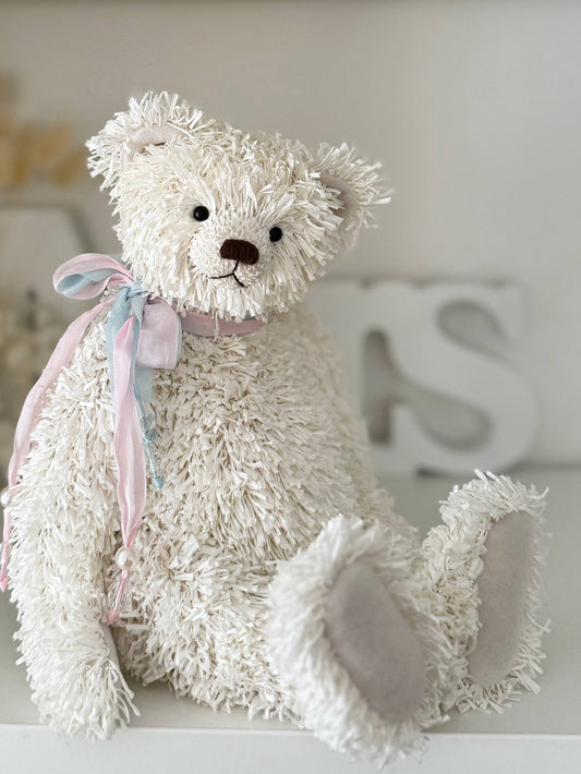 White teddy bear with a pink bow on a light background
